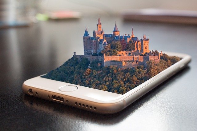 Mobilní telefon, ze kterého vystupuje 3D model hradu obklopeného lesem, ilustrace SEO trendů pro rok 2022.